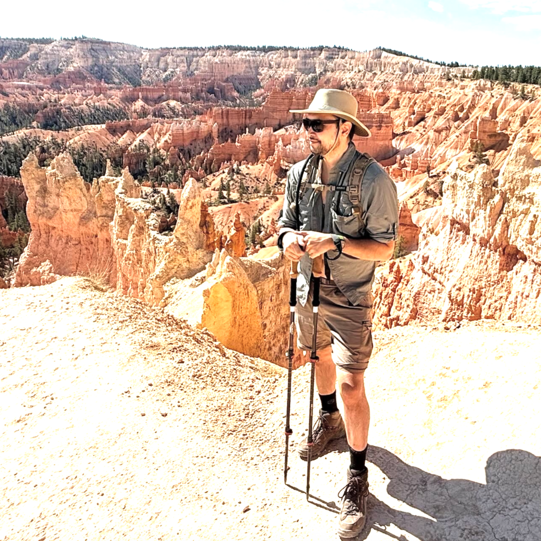 Person hiking in a canyon with rocky formations and a clear sky.