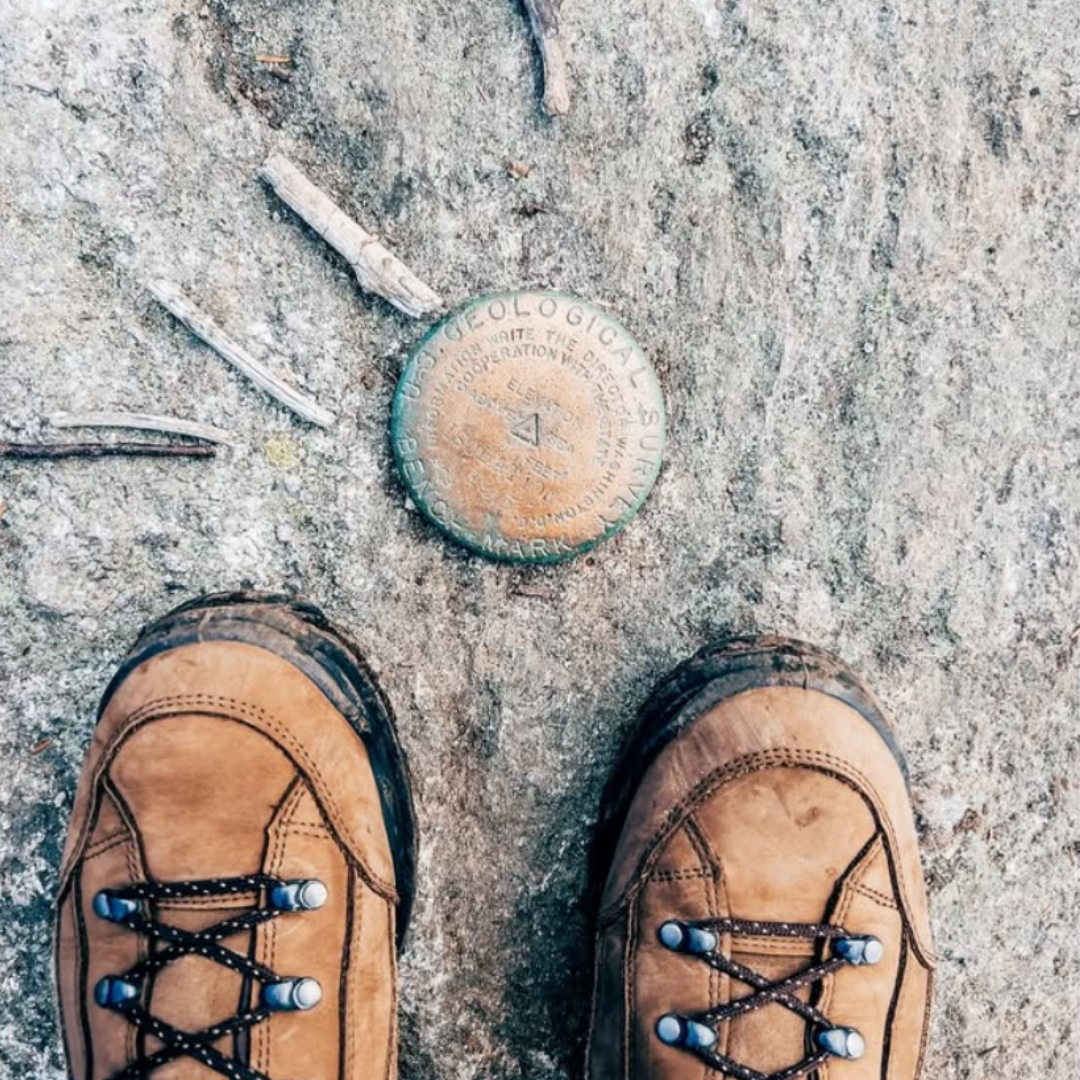 A pair of LOWA boots framing a US Geological Survey Marker on the ground
