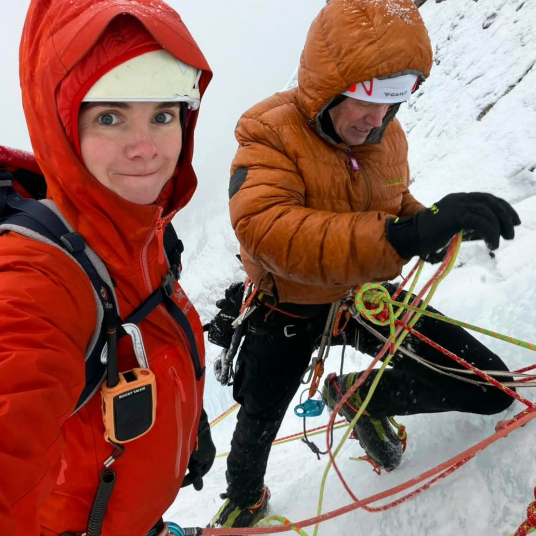 Two ice climbers on a cliff face smiling