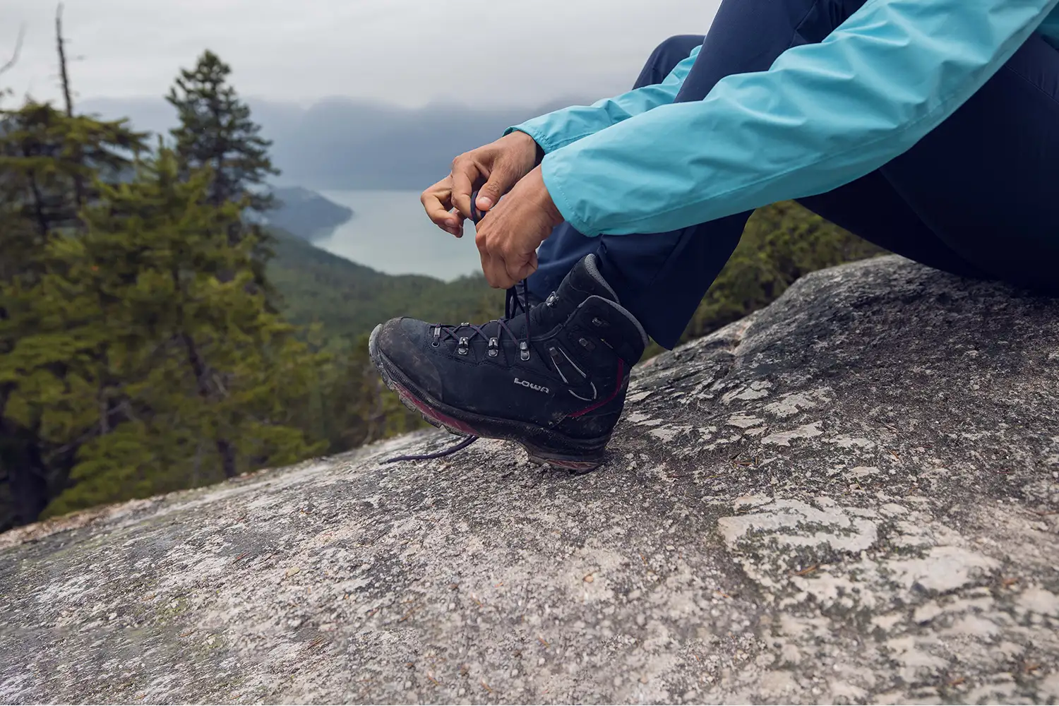 woman sitting on rock tying hiking boot