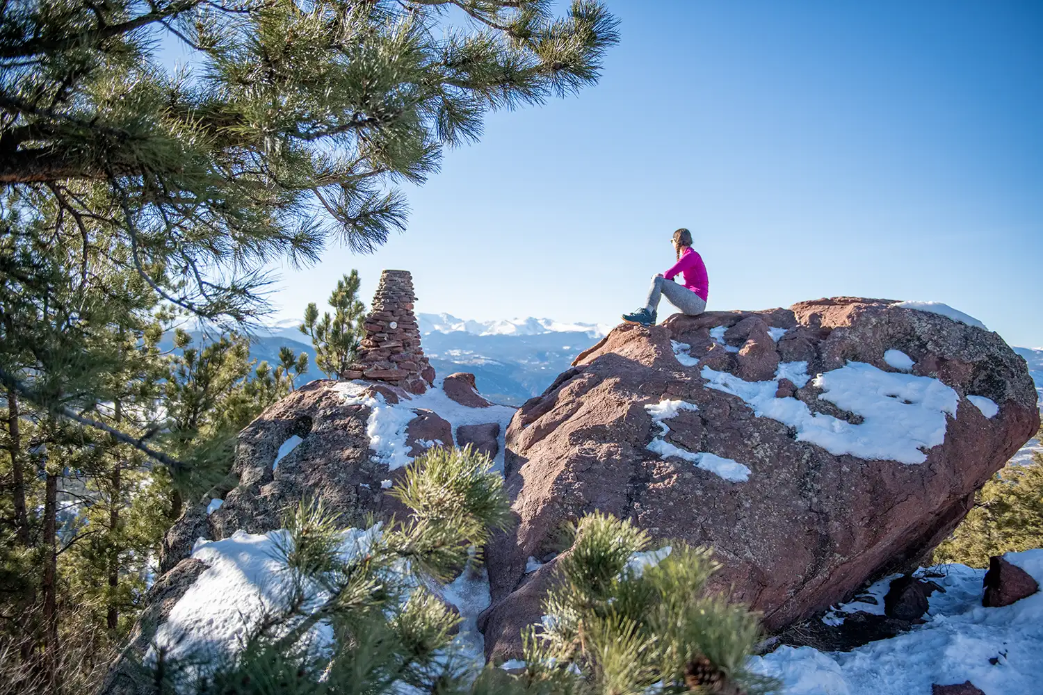Woman sitting on snow-covered rock