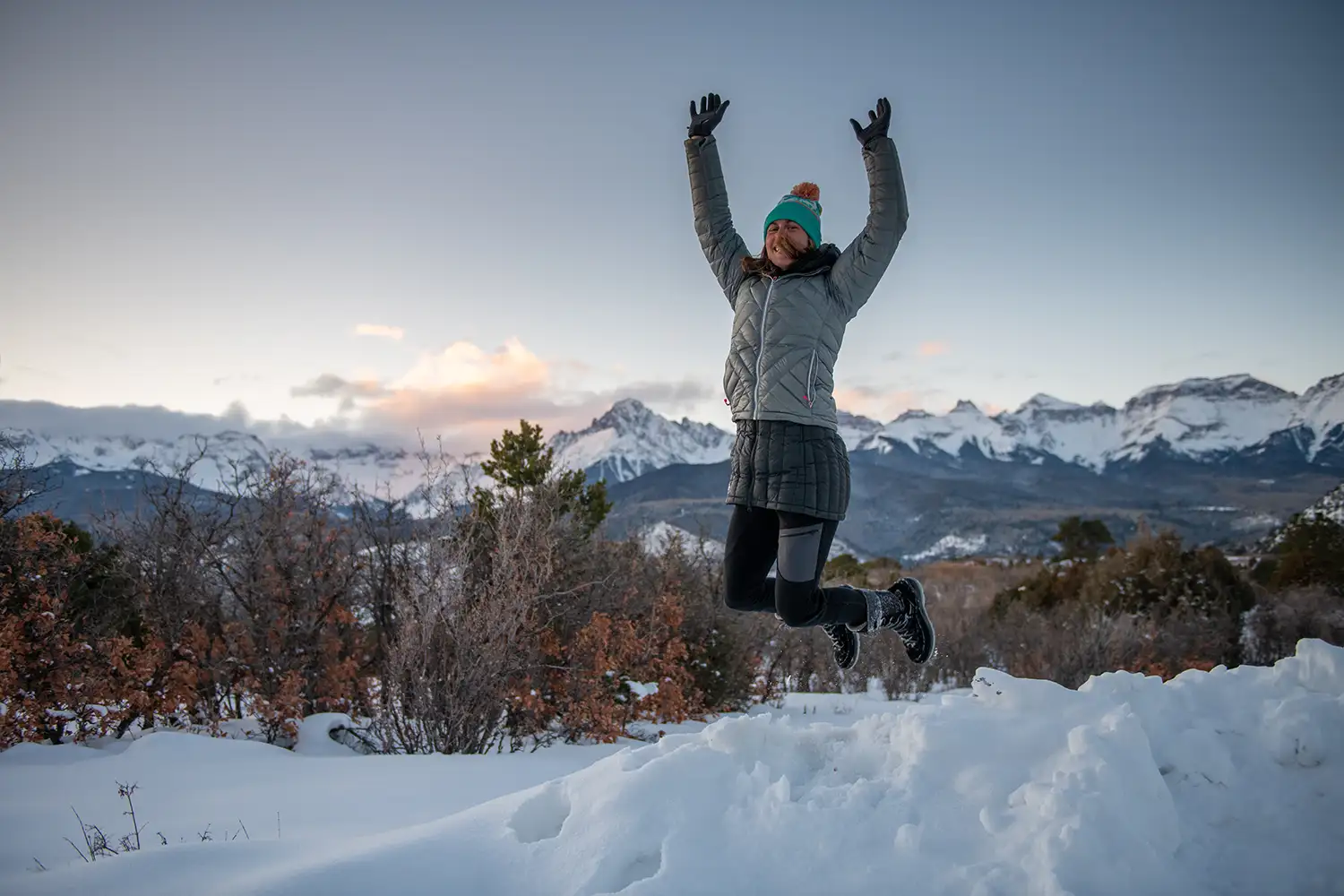 Woman jumping off snow bank