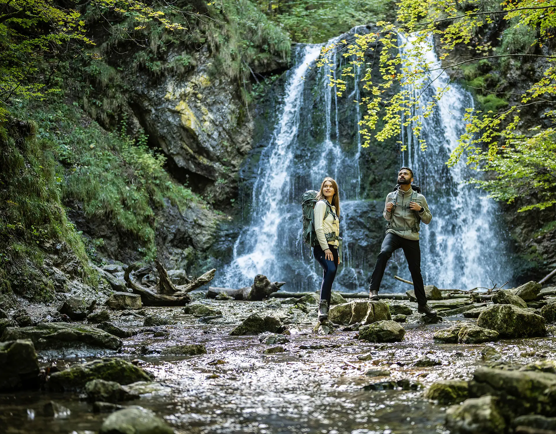 A couple of hikers standing next to waterfall