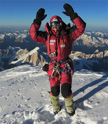 a man wearing a red jacket and standing on a snowy mountain