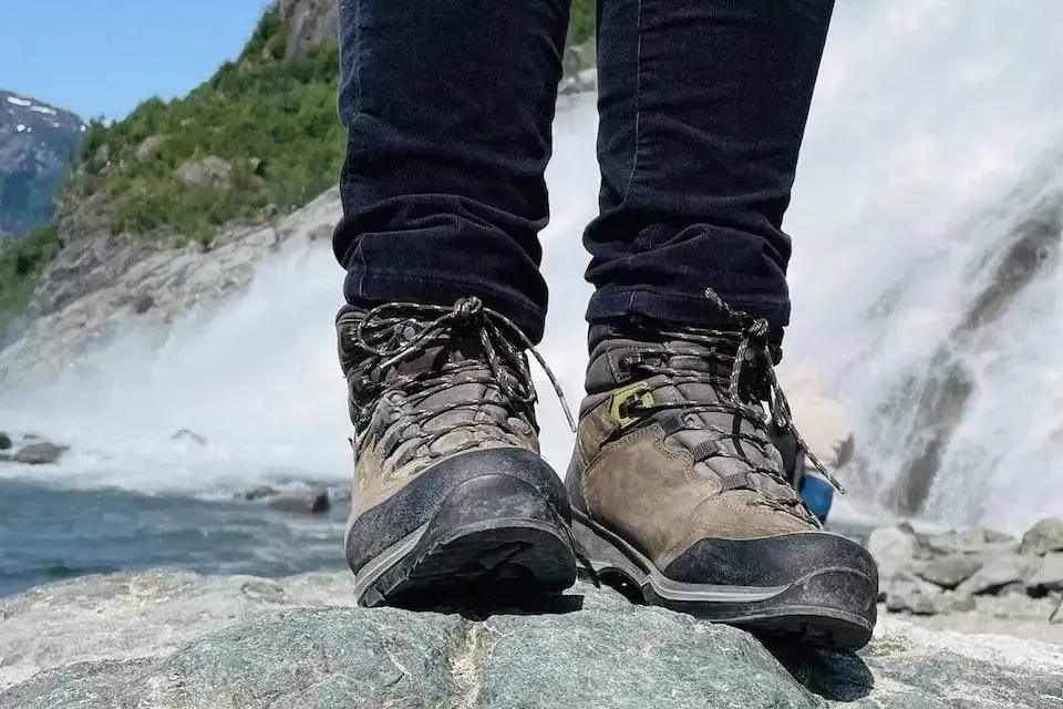 picture of boots standing on a rock with a waterfall in the background